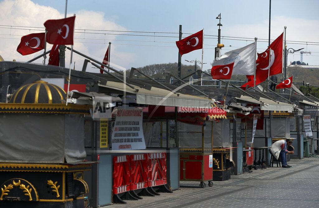 Emrah Gurel A man sits by stalls closed due to the coronavirus lockdown, at the Eminonu shopping district by the Golden Horn in Istanbul, Friday, May 1, 2020. Turkey has imposed partial lockdowns in 31 provinces every weekend and on national holidays amid the new coronavirus pandemic. (AP Photo/Emrah Gurel)