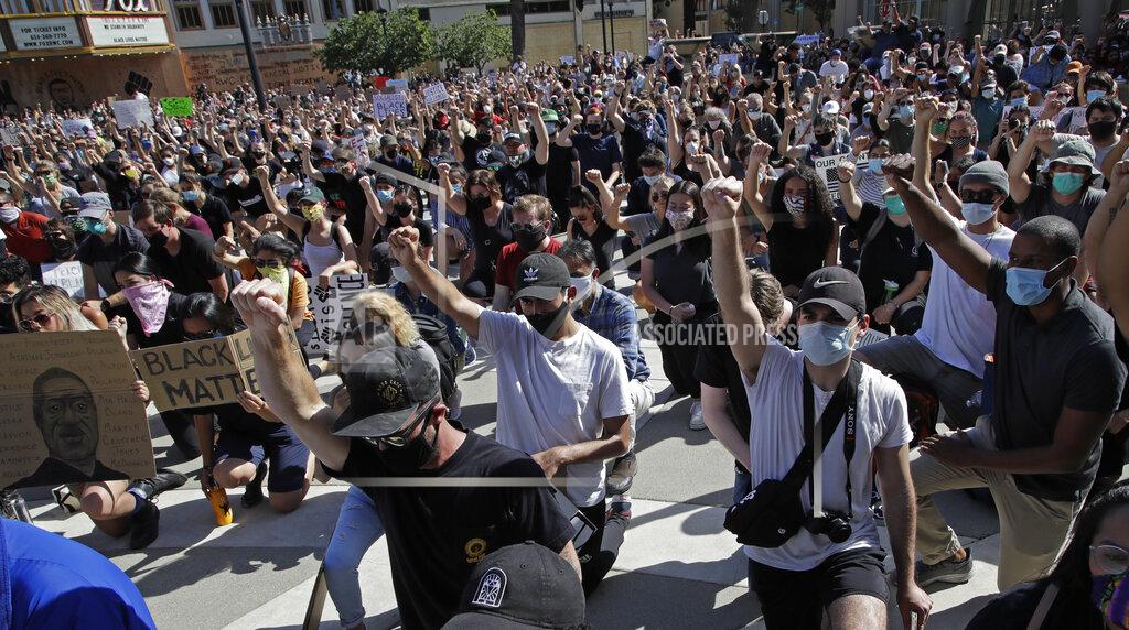 Ben Margot People raise a fist as they take a knee during a protest Tuesday, June 2, 2020, in Redwood City, Calif. (AP Photo/Ben Margot)