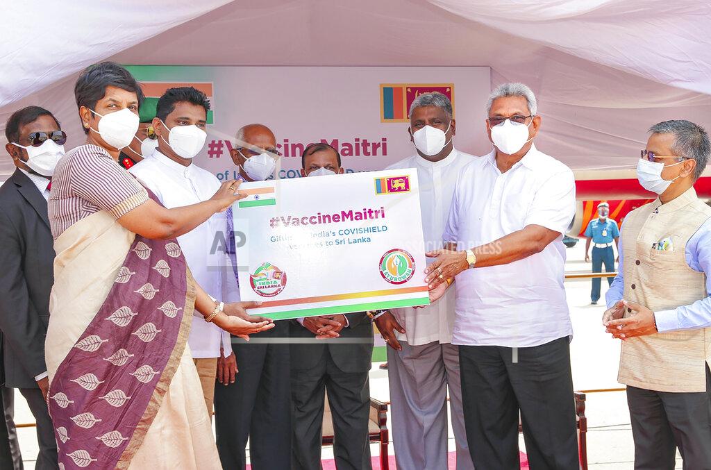 Sagara Lakmal De Mel Sri Lankan President Gotabaya Rajapaksa, second right, receives a box of COVID-19 vaccines upon arrival from India, in Colombo, Sri Lanka, Thursday, Jan. 28, 2021. Rajapaksa on Thursday welcomed the first 500,000 doses of a COVID-19 vaccine from India, which has donated the shots to eight countries in the region. (Sri Lankan Presidents Office via AP)