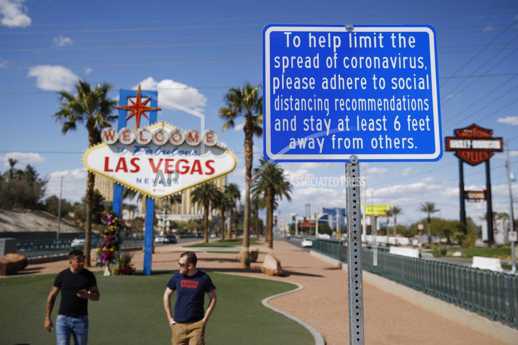 John Locher FILE - In this March 21, 2020, file photo, a sign advises people to practice social distancing to slow the spread of the coronavirus at the "Welcome to Fabulous Las Vegas Nevada" sign amid a shutdown of casinos along the Las Vegas Strip in Las Vegas. Tourists and air travelers are beginning to return to Las Vegas, but mostly by highway and well below pre-coronavirus pandemic levels, according to an airport and convention authority data released Thursday, Aug. 27, 2020.(AP Photo/John Locher, File)