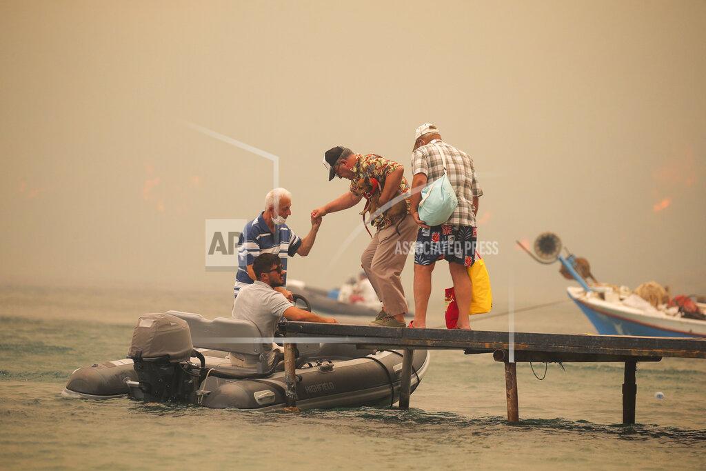 Emre Tazegul Tourists are evacuated from smoke-engulfed Mazi area as wildfires rolled down the hill toward the seashore, in Bodrum, Mugla, Turkey, Sunday, Aug. 1, 2021. More than 100 wildfires have been brought under control in Turkey, according to officials. The forestry minister tweeted that five fires are continuing in the tourist destinations of Antalya and Mugla. (AP Photo/Emre Tazegul)