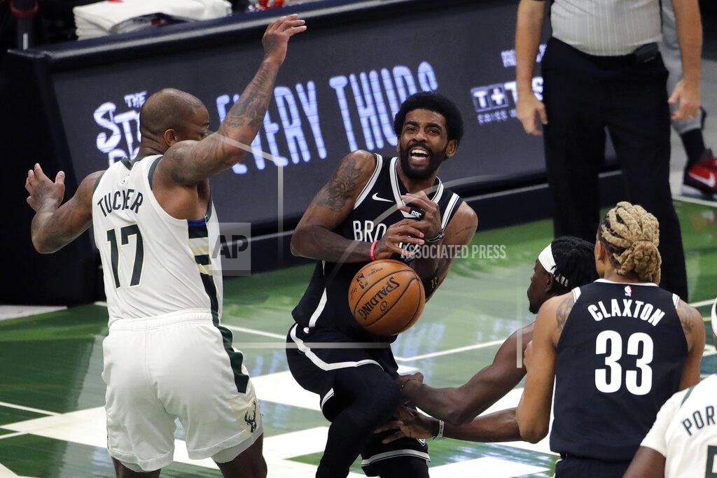 Aaron Gash Brooklyn Nets' Kyrie Irving controls the ball as he drives between Milwaukee Bucks' P.J. Tucker (17) and Jrue Holiday during the first half of an NBA basketball game Tuesday, May 4, 2021, in Milwaukee. (AP Photo/Aaron Gash)