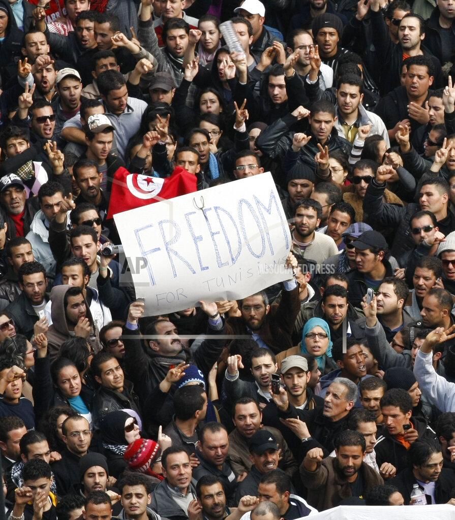 Christophe Ena Protesters chant slogans against President Zine El Abidine Ben Ali in Tunis, Friday, Jan. 14, 2011. Some thousands of angry demonstrators marched through the Tunisian capital Friday, demanding the resignation of the country's autocratic leader a day after he appeared on TV to try to stop deadly riots that have swept the North African nation. On Thursday Jan. 14, 2021, Tunisia commemorates 10 years since the flight into exile of its iron-fisted leader, Zine El Abidine Ben Ali, pushed from power in a popular revolt that foreshadowed the so-called Arab Spring. (AP Photo/Christophe Ena)