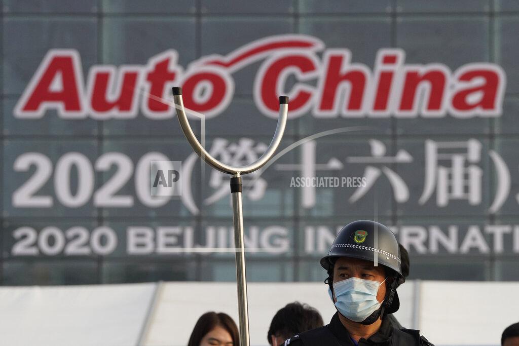 Ng Han Guan A security guard wearing mask and armed with a restrainer stands guard at the entrance to the Auto China 2020 show in Beijing, China on Saturday, Sept. 26, 2020. The auto show, the first major in-person sales event for any industry since the coronavirus pandemic began, opens Saturday in a sign the ruling Communist Party is confident China has contained the disease. Still, automakers face intensive anti-virus controls including quarantines for visitors from abroad and curbs on crowd sizes at an event that usually is packed shoulder-to-shoulder with spectators. (AP Photo/Ng Han Guan)