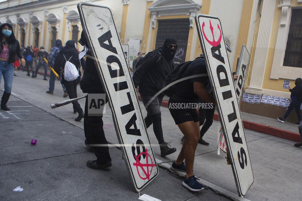 Oliver De Ros Demonstrators use transits signs as shields in front of the Congress building after protesters set a part of the building on fire, in Guatemala City, Saturday, Nov. 21, 2020. Hundreds of protesters were protesting in various parts of the country Saturday against Guatemalan President Alejandro Giammattei and members of Congress for the approval of the 2021 budget that reduced funds for education, health and the fight for human rights. (AP Photo/Oliver De Ros)