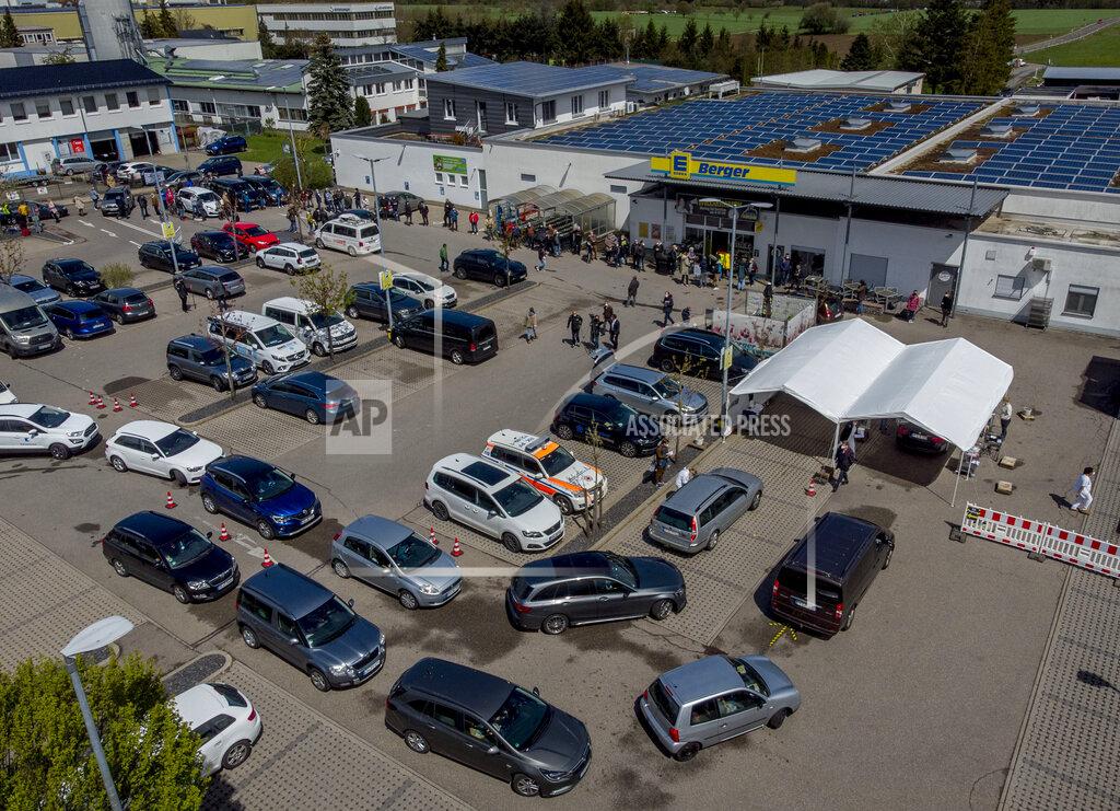 Cars with people waiting for AstraZeneca vaccination queue in front of a tent on the parking lot of a supermarket in Pforzheim, southern Germany, Wednesday, May 5, 2021. A doctor who could not get rid of her AstraZeneca vaccine in her doctor's office decided to offer some 250 doses in drive-in location at the supermarket. (AP Photo/Michael Probst)
