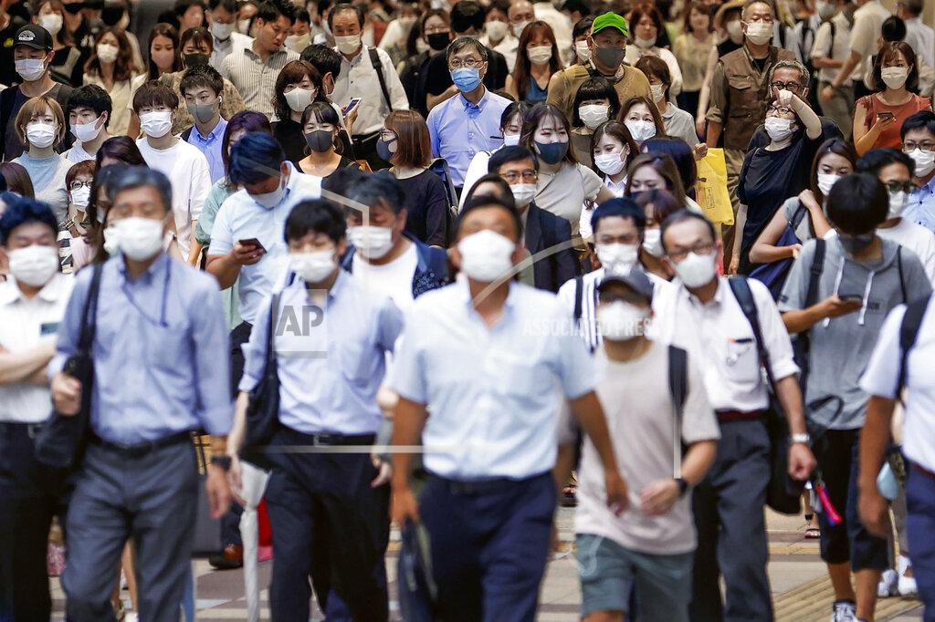 115323+0900 People wearing face masks to help curb the spread of the new coronavirus walk across a street in Osaka, Japan, Wednesday, July 29, 2020. As Japan battles a surge in coronavirus cases, some areas may be running out of isolation facilities to monitor infected people.(Kyodo News via AP)