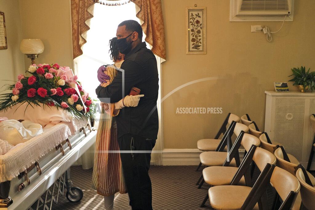 Seth Wenig FILE - In this May 2, 2020, file photo, siblings Erika and Dwayne Bermudez comfort one another during a short viewing of their mother, Eudiana Smith, who died of coronavirus, at The Family Funeral Home in Newark, N.J. "I was robbed of the experience of being able to celebrate her life in a manner that would offer some kind of respect for the woman she was," Erika Bermudez said. She did her best, live-streaming the ceremony to friends and family who couldn't attend. (AP Photo/Seth Wenig)