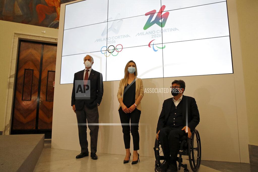 Alessandra Tarantino From left, Italian National Olympic Committee (CONI) President Giovanni Malago, Cabinet Undersecretary and Olympic champion Valentina Vezzali, and Italy's Paralympic Committee President Luca Pancalli pose in front of the logo of 2026 Milan-Cortina Olympics and Paralympics, right, during a press conference in Rome, Tuesday, March 30, 2021. A futuristic white-on-white logo was unveiled as the emblem for the 2026 Milan-Cortina Olympics on Tuesday following an online vote. Nearly a million votes were cast, 871,566 to be exact, over the last two weeks from Italy and 168 other nations for the two finalists. The “Futura” logo received 75 percent of the votes, winning easily ahead of the more traditional “Dado” option. (AP Photo/Alessandra Tarantino)
