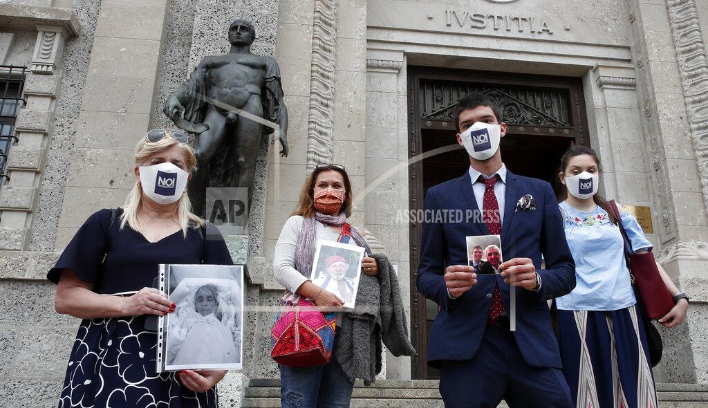 FILE - In this June 10, 2020 file photo, from left, Laura Capella, Nicoletta Bosica, Stefano Fusco and Arianna Dalba hold pictures of their relatives, victims of COVID-19, as they stand in front of Bergamo's courthouse, Italy. Italy is poised to reclaim the dishonor of reporting the most coronavirus deaths in Europe, as the second surge ravages the country’s disproportionately old population and exposes how public health shortfalls and delayed restrictions compounded a lack of preparedness going into the pandemic. (AP Photo/Antonio Calanni, file)