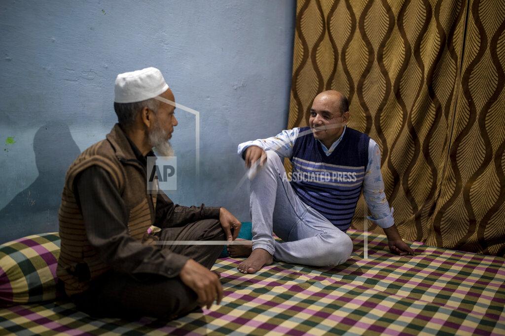 Altaf Qadri Muhammad Nasir Khan, right,who was shot by a Hindu mob during the February 2020 communal riots, speaks to his father Abdul Jaleel inside his home in North Ghonda, one of the worst riot affected neighborhood, in New Delhi, India, Friday, Feb. 19, 2021. As the first anniversary of bloody communal riots that convulsed the Indian capital approaches, Muslim victims are still shaken and struggling to make sense of their struggle to seek justice. (AP Photo/Altaf Qadri)