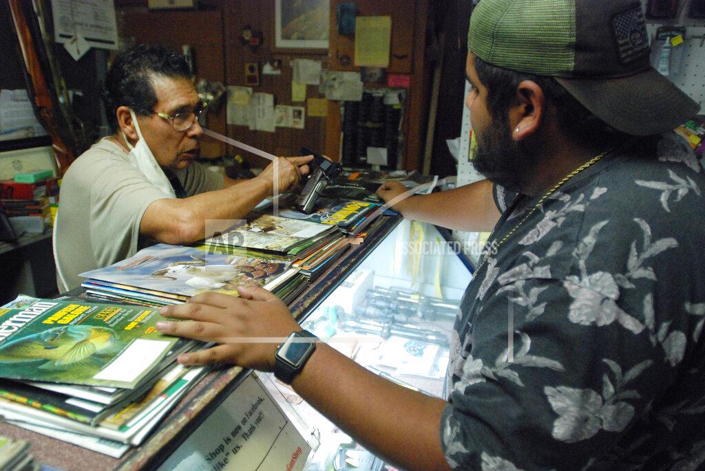 Morgan Lee Gun shop owner Jesus "Chuy" Aguirre attends to customer Angel Zacarias on Thursday, Aug. 26, 2021, in Chuy's Gun Shop in El Paso, Texas, as anticipation builds regarding a new Texas law that relaxes restrictions on handguns. Under the new law, most people age 21 or older who have not been convicted of a felony can carry a holstered handgun — concealed or not — in public without getting a license and related training. Supporters say the changes are a necessary expansion of the so-called constitutional carry movement that will allow people to more easily defend themselves without government interference. (AP Photo/Morgan Lee)