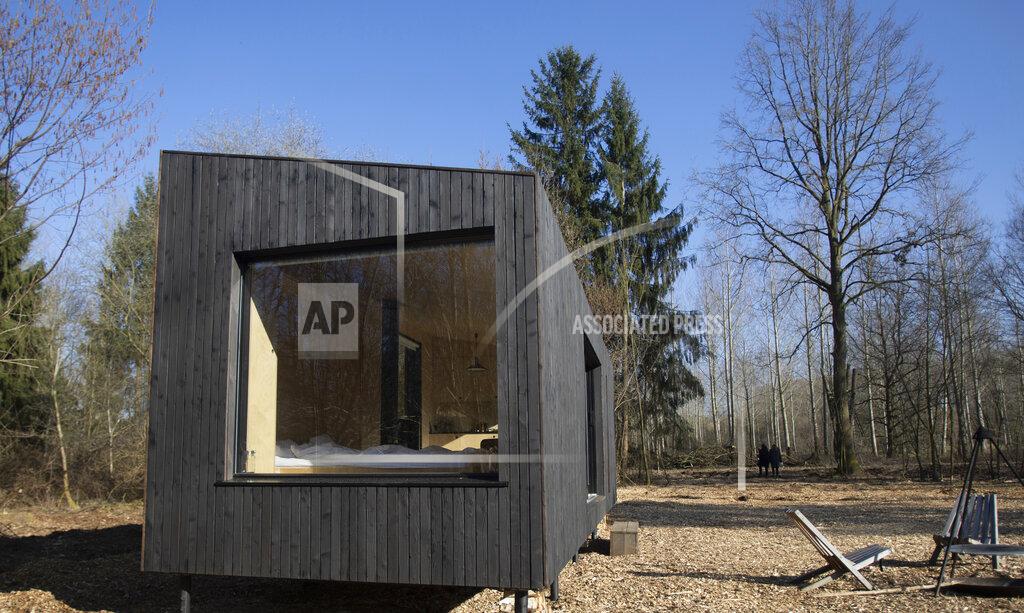 Virginia Mayo A couple go for a walk in the woods near a Slow Cabin in Zandbergen, Belgium, Sunday, Feb. 28, 2021. These Slow Cabins, set up the Belgian countryside, are the new way to vacation in pandemic times: in complete solitude and in the middle of nowhere. The wooden cabins are fully sustainable, provided you don't stay in the shower too long and you can live without Wi-Fi. (AP Photo/Virginia Mayo)