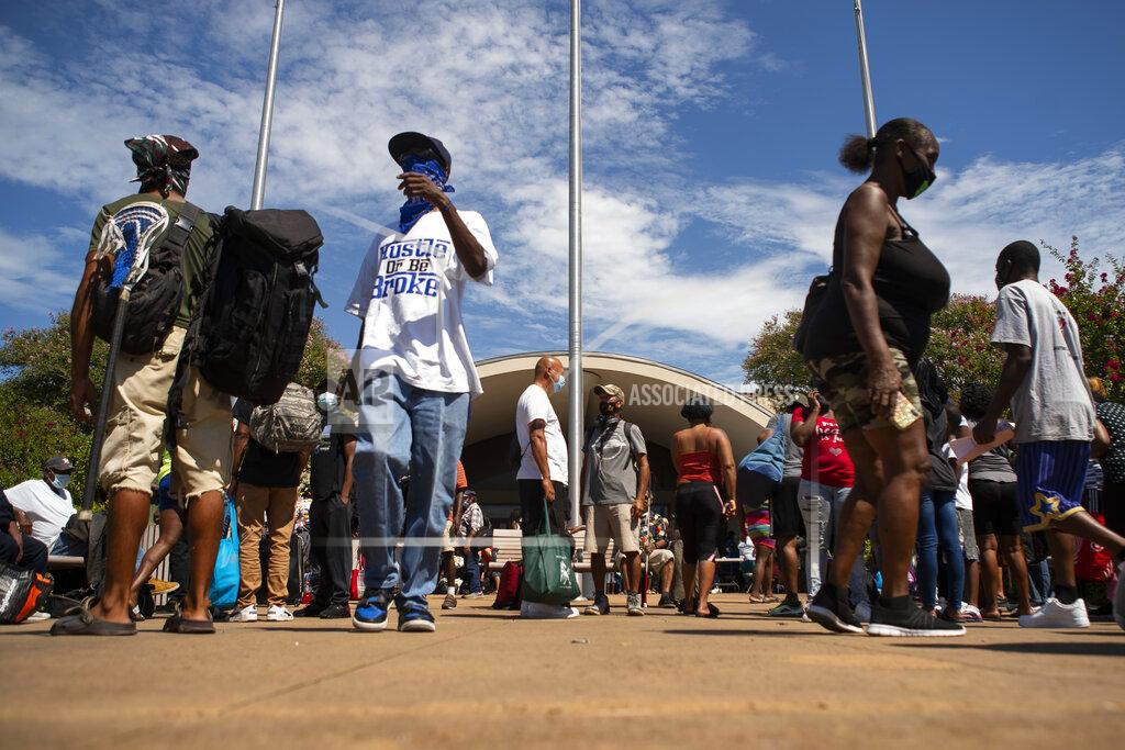 Mark Mulligan People wait in front of the Galveston Housing Authority offices to board charter busses that will evacuate them from Galveston Island to Austin in anticipation of impact from Hurricane Laura, Tuesday, Aug. 25, 2020, in Galveston. ( Mark Mulligan/Houston Chronicle via AP)