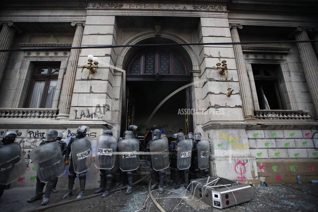 Moises Castillo Police surround the Congress building after protesters set a part of it on fire, in Guatemala City, Saturday, Nov. 21, 2020. Hundreds of protesters were protesting in various parts of the country Saturday against Guatemalan President Alejandro Giammattei and members of Congress for the approval of the 2021 budget that reduced funds for education, health and the fight for human rights. (AP Photo/Moises Castillo)
