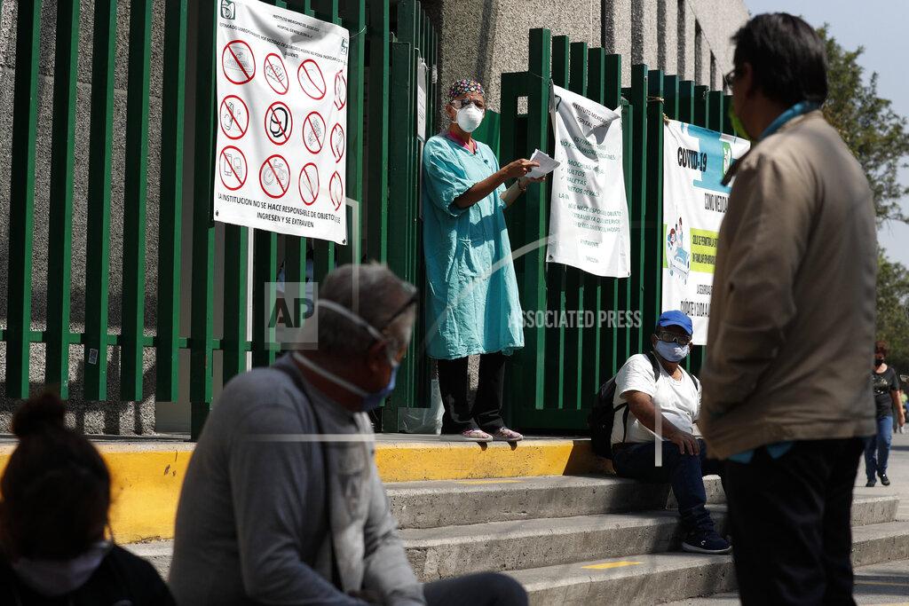 Rebecca Blackwell A hospital worker calls out a name from the gate, as relatives of hospitalized patients wait outside in hopes of receiving news of their loved ones, at a public hospital in the Iztapalapa district of Mexico City, Tuesday, May 5, 2020. Iztapalapa has the most confirmed cases of the new coronavirus within Mexico's densely populated capital, itself one of the hardest hit areas of the country with thousands of confirmed cases and around 500 deaths.(AP Photo/Rebecca Blackwell)