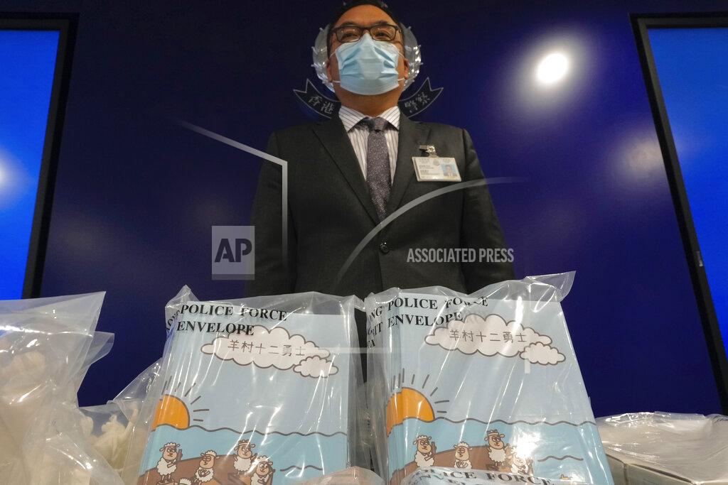 Vincent Yu Li Kwai-wah, senior superintendent of Police National Security Department, poses in front of evidence including three children's books on stories that revolve around a village of sheep which has to deal with wolves from a different village, before a press conference in Hong Kong Thursday, July 22, 2021. Hong Kong's national security police on Thursday arrested five people from a trade union of the General Association of Hong Kong Speech Therapists on suspicion of conspiring to publish and distribute seditious material, in the latest arrests made amid a crackdown on dissent in the city. (AP Photo/Vincent Yu)