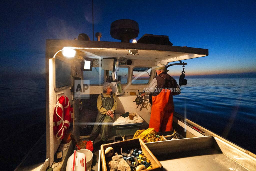 Robert F. Bukaty Virginia Oliver, left, chats with her son Max Oliver while heading out to sea to fish for lobster at dawn, Tuesday, Aug. 31, 2021, off Rockland, Maine. Virginia Oliver, age 101, is the state's oldest lobster fisher. (AP Photo/Robert F. Bukaty)