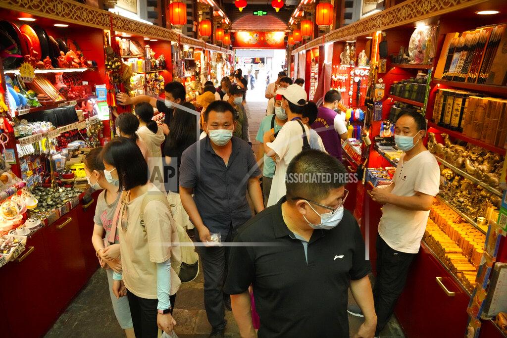 Mark Schiefelbein Visitors wear face masks to protect against COVID-19 as they walk at a tourist shopping street in Beijing, Tuesday, Aug. 3, 2021. Chinese authorities announced Tuesday mass coronavirus testing in Wuhan as an unusually wide series of COVID-19 outbreaks reached the city where the disease was first detected in late 2019. The current outbreaks, while still in the hundreds of cases in total, have spread much more widely than previous ones, reaching multiple provinces and cities including the capital, Beijing. (AP Photo/Mark Schiefelbein)