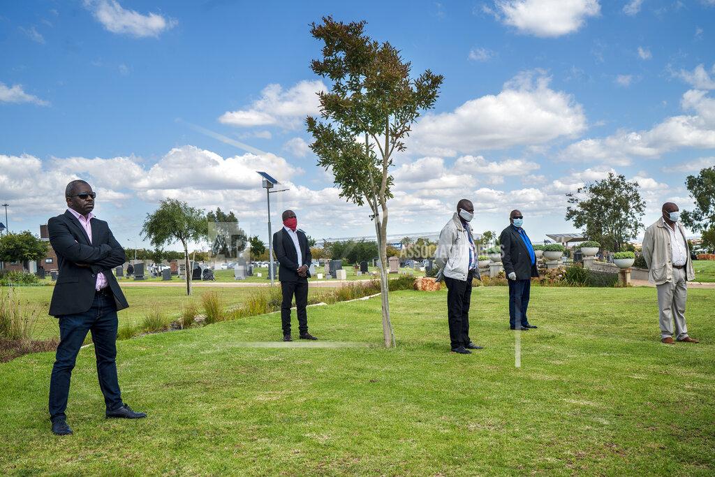 Jerome Delay Family and friends observe social distancing during the funeral ceremony for Benedict Somi Vilakasi at the Nasrec Memorial Park outside Johannesburg Thursday, April 16, 2020. Vilakasi, a Soweto coffee shop manager, died of COVID-19 infection in a Johannesburg hospital Sunday April 12 2020. South Africa is under a strict five-week lockdown in a effort to fight the Coronavirus pandemic. (AP Photo/Jerome Delay)