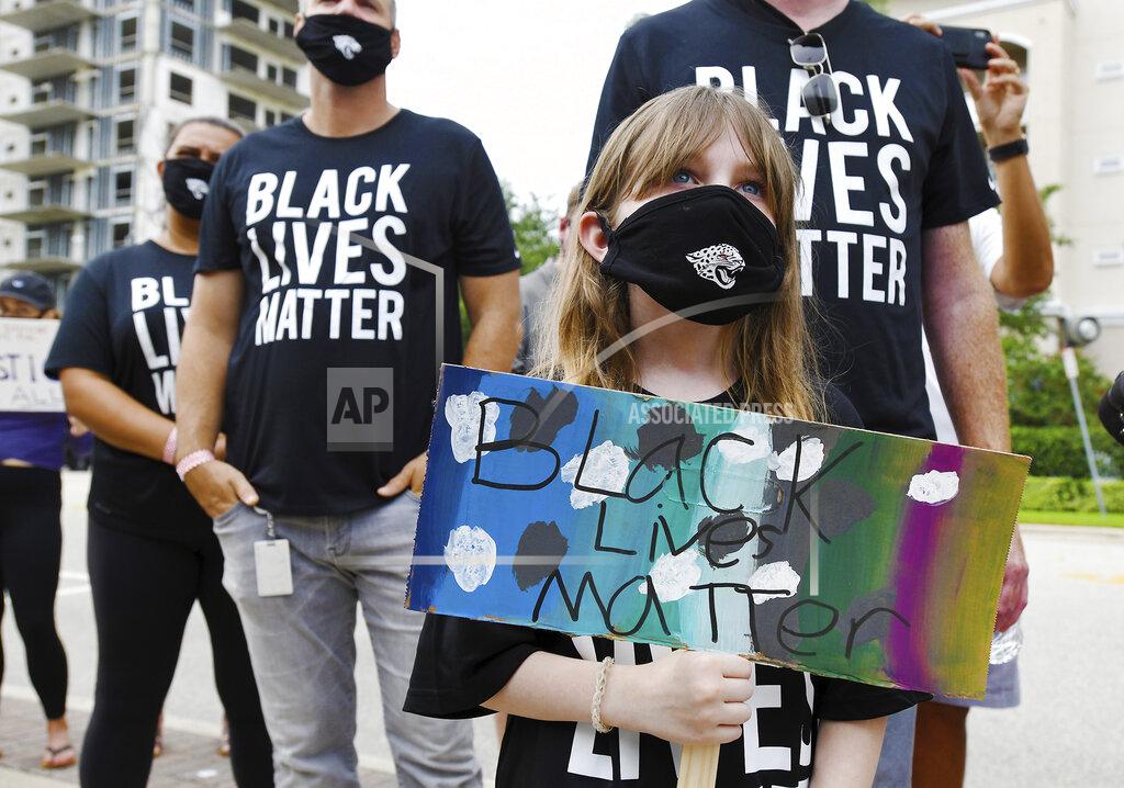 Caroline Youell, 9 holds her Black Lives Matter sign as she joins Jacksonville Jaguars NFL football players and their staff and families in a rally on the steps of the Jacksonville Sheriffs Office, Friday morning, June 5, 2020, in Jacksonville, Fla., as they protest against inequality and police brutality. (Bob Self/The Florida Times-Union via AP)