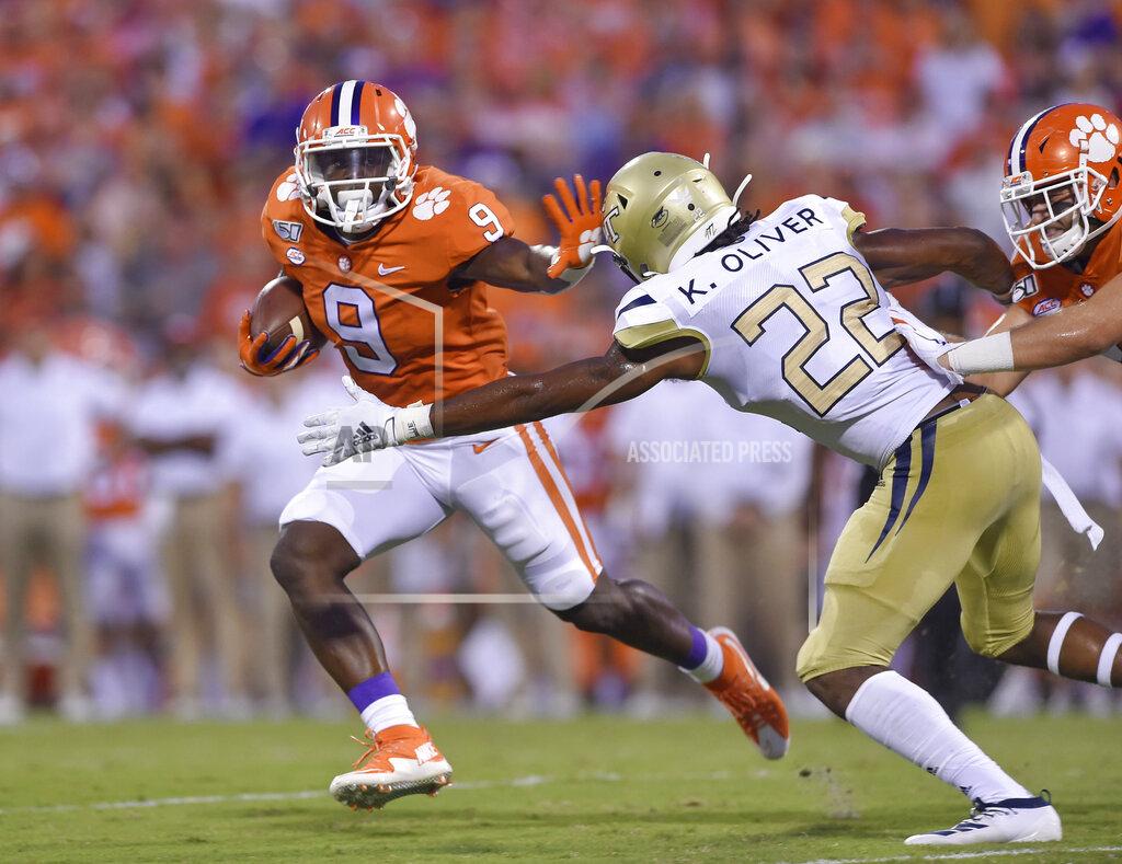 Clemson's Travis Etienne (9) fends off Georgia Tech's Kaleb Oliver to gain a first down during the first half of an NCAA college football game Thursday, Aug. 29, 2019, in Clemson, S.C. (AP Photo/Richard Shiro)