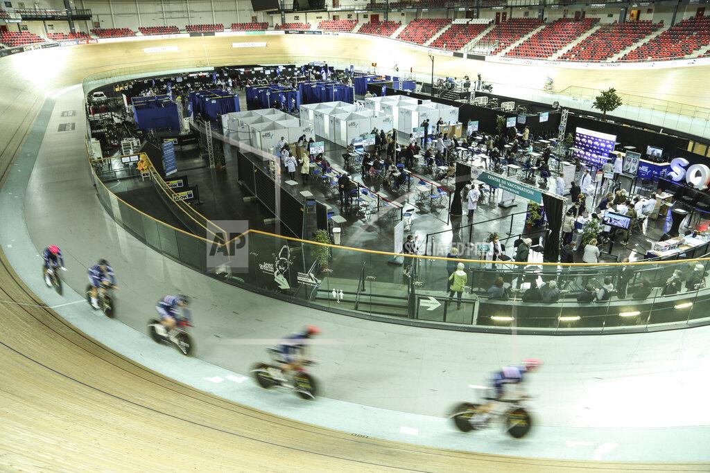 Riders train at the National Velodrome at Saint-Quentin-en-Yvelines, west of Paris, Saturday, March 27, 2021, that has been transformed into a mass vaccination center. Saturday marked the first day in France of vaccination for healthy people aged 70 and above. (AP Photo/John Leicester)