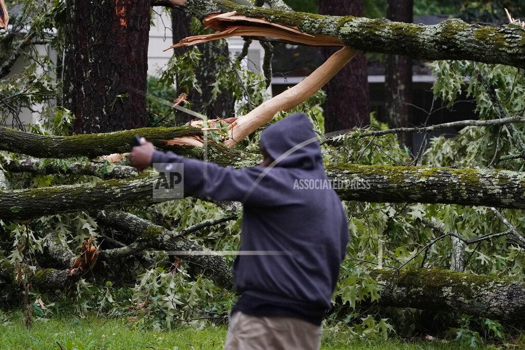 Rogelio V. Solis A northeast Jackson, Miss., talks to a friend on a phone as he inspects the wind toppled trees in his neighborhood, Tuesday, May 4, 2021. The severe weather was not unexpected, since the state was hit with a number of tornadoes on Sunday. (AP Photo/Rogelio V. Solis)