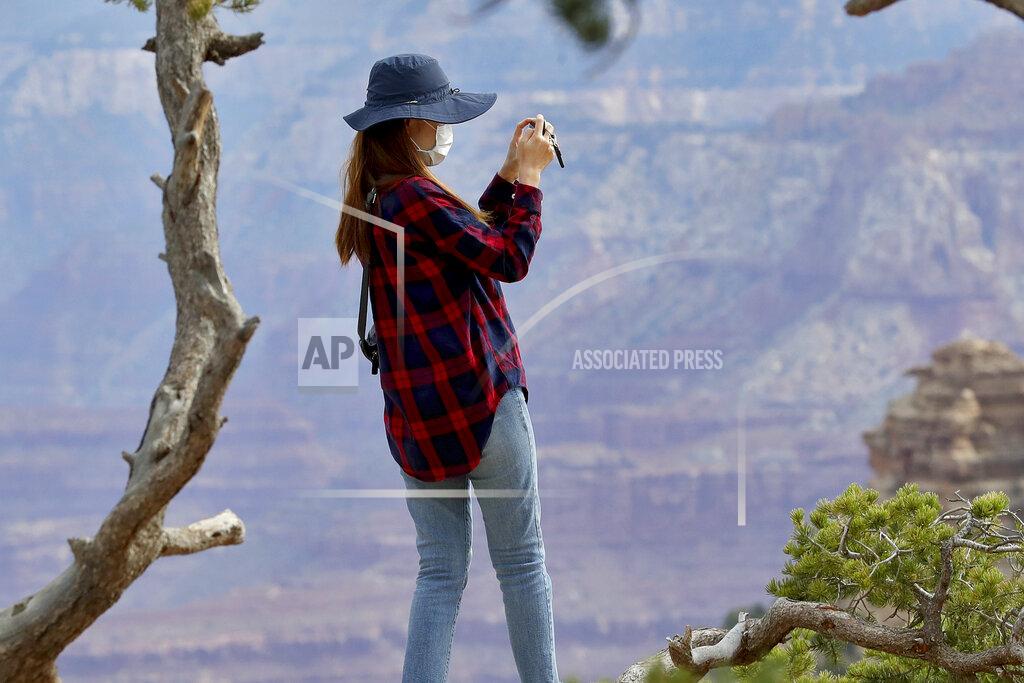 Matt York A visitor takes a photo at the Grand Canyon Friday, May 15, 2020, in Grand Canyon, Ariz. Tourists are once again roaming portions of Grand Canyon National Park when it partially reopened Friday morning, despite objections that the action could exacerbate the coronavirus pandemic. (AP Photo/Matt York)