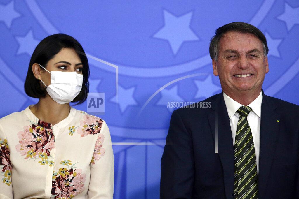 Eraldo Peres Brazil's President Jair Bolsonaro smiles sitting next to his wife Michelle Bolsonaro wearing a protective face mask, during the swearing ceremony of his new justice minister, at the Planalto presidential palace, in Brasilia, Brazil, Wednesday, April 29, 2020. (AP Photo/Eraldo Peres)