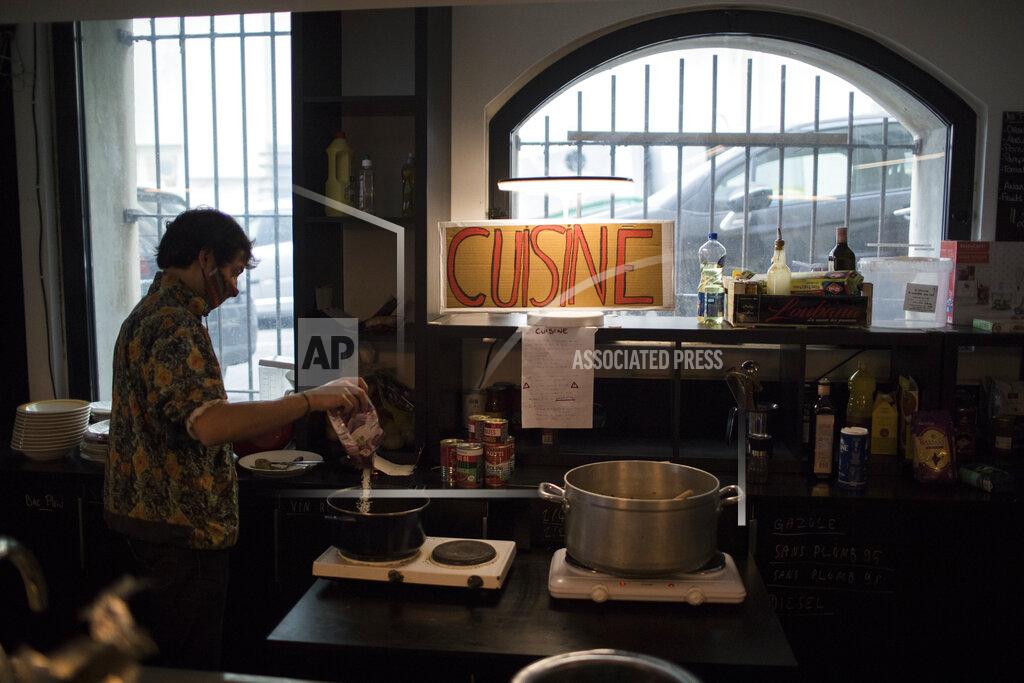 Daniel Cole A culture worker cooks food in a makeshift kitchen at the occupied Theatre de La Criee in Marseille, southern France, Friday, March 26, 2021. Out-of-work French culture and tourism workers are occupying theaters accross France to demand more government support after a year of pandemic that has devastated their incomes and put their livelihoods on indefinite hold. (AP Photo/Daniel Cole)
