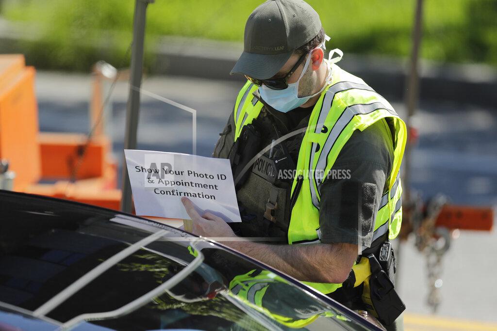Brynn Anderson An official holds a sign telling people to "Show Your Photo ID and Appointment Confirmation" to help guide patients to a COVID-19 testing area on Georgia Tech's campus, Monday, April 6, 2020, in Atlanta. (AP Photo/Brynn Anderson)