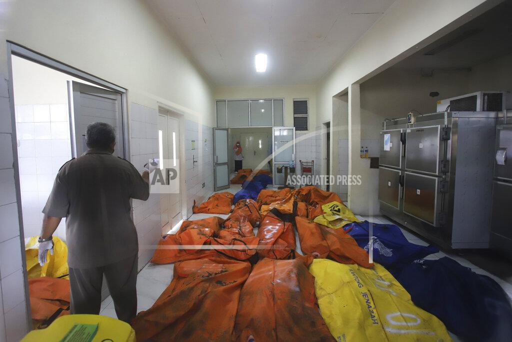 Uncredited Staff members stand among body bags containing the bodies of the victims of a prison fire at the local hospital's morgue in Tangerang on the outskirts of Jakarta, Indonesia, Wednesday, Sept. 8, 2021. A massive fire raged through an overcrowded prison near Indonesia's capital early Wednesday, killing a number of inmates. (AP Photo)