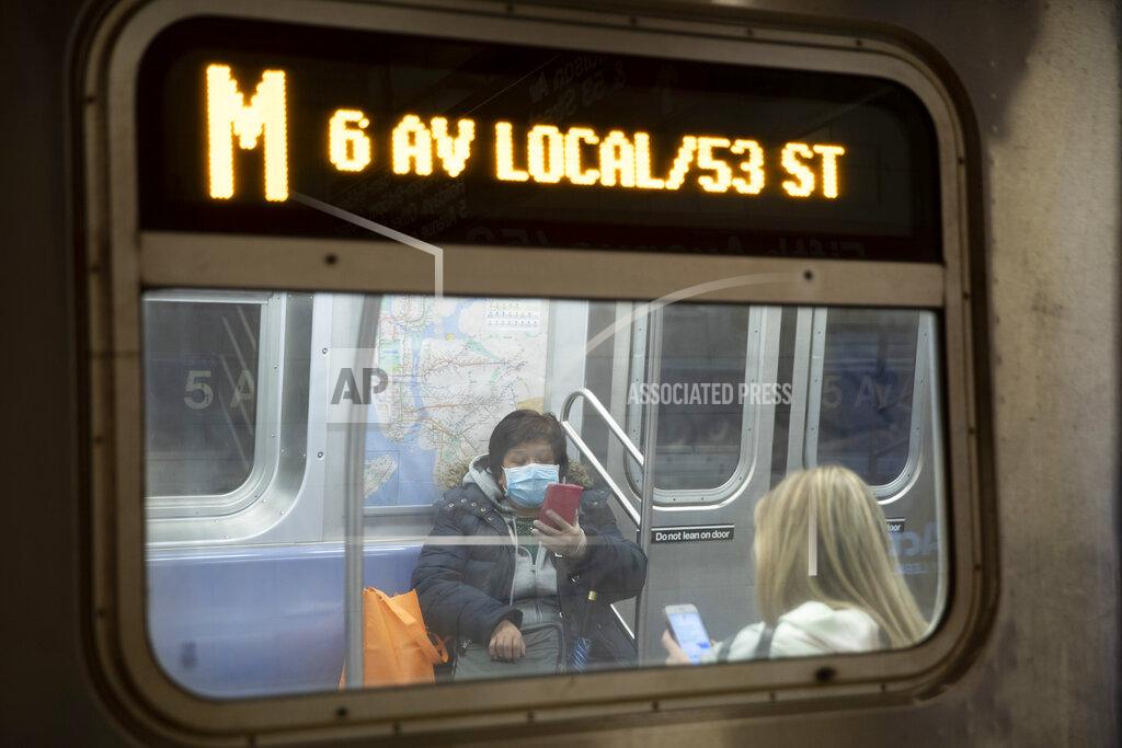 FILE- In this March 19, 2020 file photo, a commuter wears a face mask while riding the subway in New York. Commuters who refuse to wear a mask on New York City subways, trains and buses could be fined $50 starting Monday, Sept. 14, 2020. (AP Photo/Mary Altaffer, File)