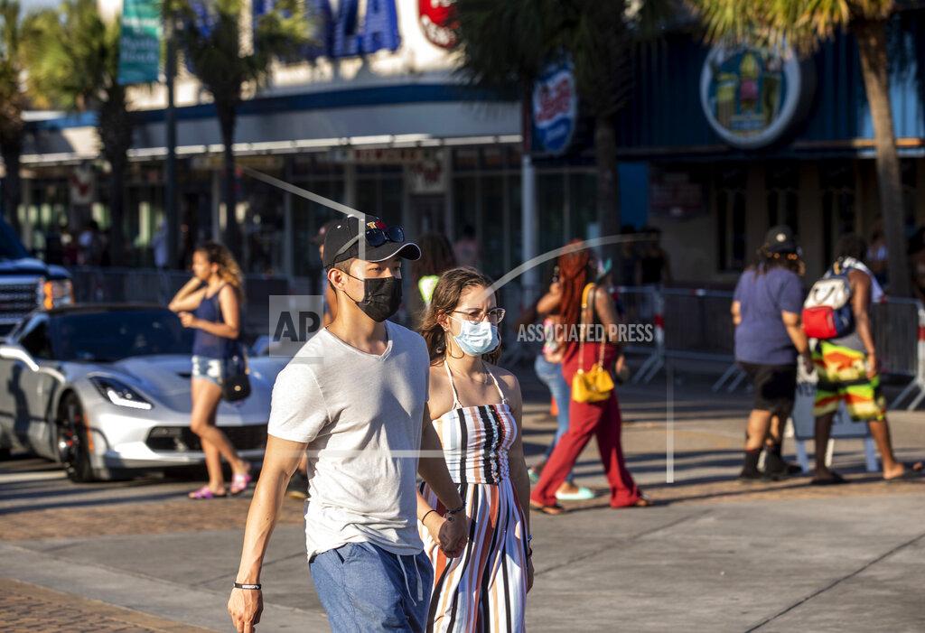 Jason Lee Tourists, some wearing masks, walk along Ocean Boulevard amid the coronavirus pandemic, Saturday, May 23, 2020, in Myrtle Beach, S.C. (Jason Lee/The Sun News via AP)