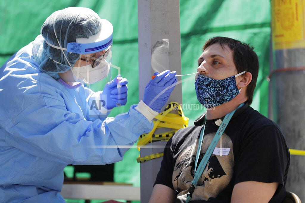 Ted S. Warren FILE - In this May 16, 2020, file photo, Tina Nguyen, left, a nurse at the International Community Health Services clinic in Seattle's International District, takes a nose swab sample from David Carroll, an ICHS employee, during testing for the coronavirus in Seattle. At a cost of $120-130 per test and NHL Commissioner Gary Bettman’s estimate the league will need 25,000-35,000 in total to get through the playoffs, the price tag he concedes is “millions of dollars.” But regular testing is something players insisted on in the name of feeling safe to compete.(AP Photo/Ted S. Warren, File)