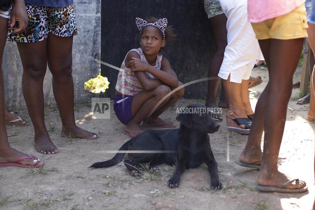 Silvia Izquierdo A girl waits for food donated by the Covid Without Hunger organization in the Jardim Gramacho slum of Rio de Janeiro, Brazil, Saturday, May 22, 2021. As incomes fall, prices are surging, which means the disadvantaged are doubly squeezed. (AP Photo/Silvia Izquierdo)