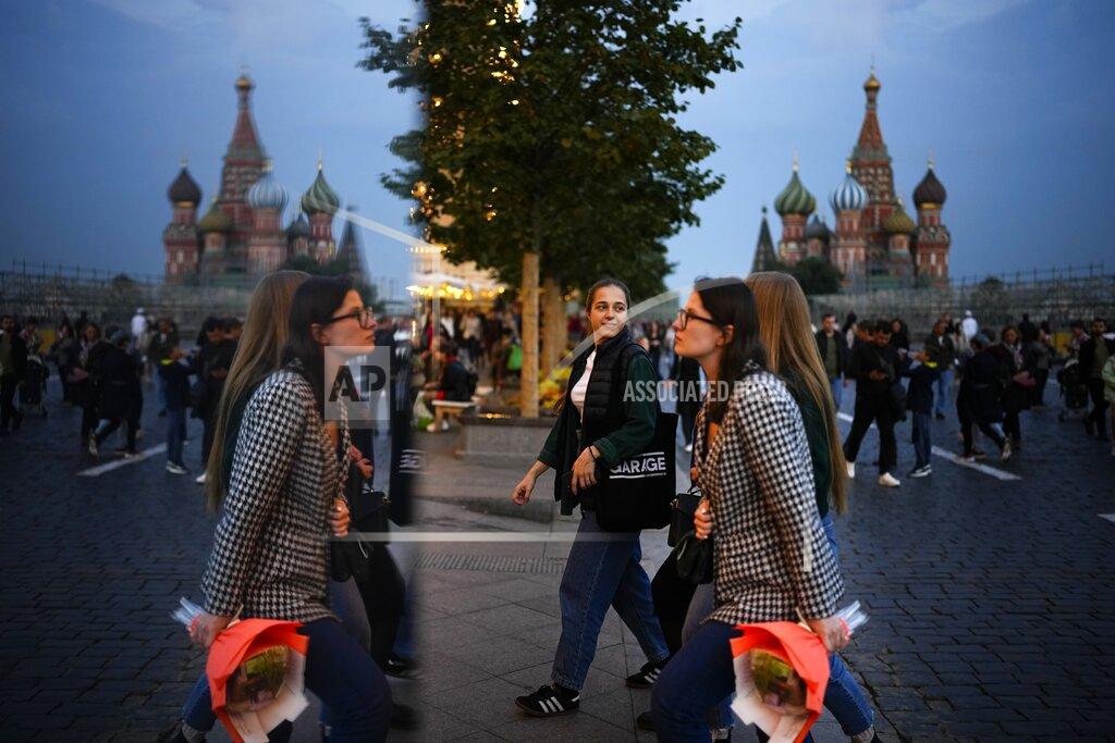 People walk reflecting in a mirror installation after sunset in Red Square in Moscow, Russia, Sunday, Sept. 12, 2021. (AP Photo/Alexander Zemlianichenko)