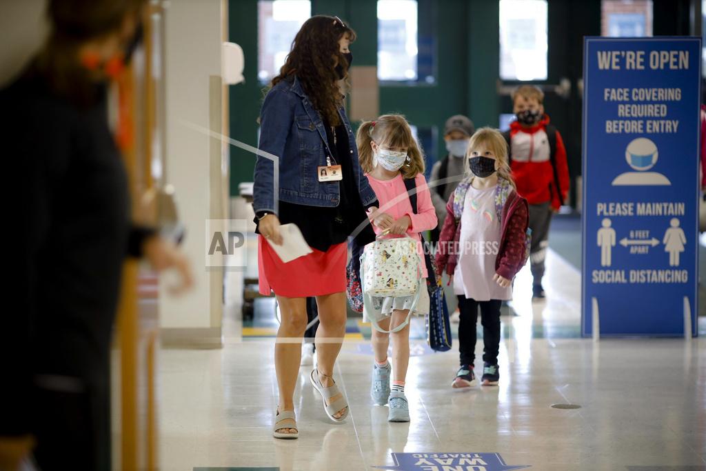 Stephanie Zollshan Kindergarten students are led into the building on the first day of in-person classes at Lee Elementary School on Wednesday, Sept. 16, 2020 in Lee, Mass. (Stephanie Zollshan/The Berkshire Eagle via AP)