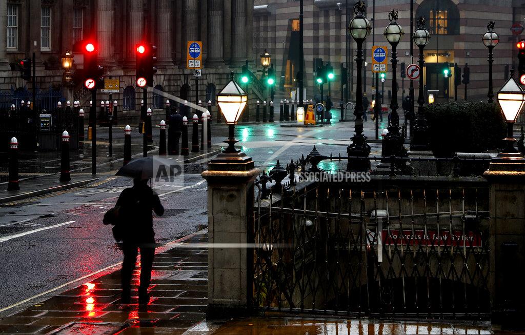 A man with an umbrella walks through a street in the financial area of London, Wednesday, Jan. 13, 2021 during England's third national lockdown to curb the spread of coronavirus. (AP Photo/Alastair Grant)
