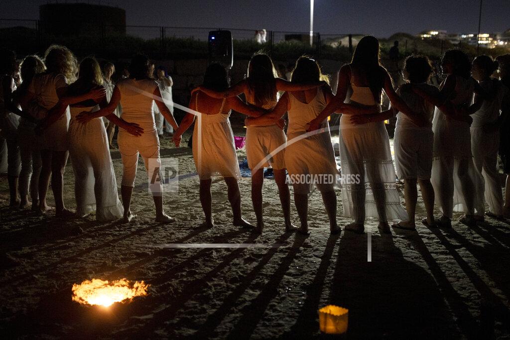 Maya Alleruzzo Women take part in a Tashlich ceremony, where they wrote down things they want to release before casting them into a fire, on the beach in Tel Aviv, Israel, Tuesday, Sept. 14, 2021. Tashlich, which means 'to cast away' in Hebrew, is the practice by which Jews go to a large flowing body of water and symbolically 'throw away' their sins by throwing a piece of bread, or similar food, into the water before the Jewish holiday of Yom Kippur, the holiest day in the Jewish year which starts at sundown Wednesday. (AP Photo/Maya Alleruzzo)