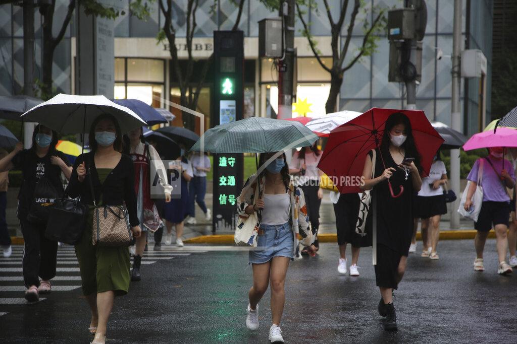 Chen Si Residents using umbrellas cross an intersection in Shanghai, China, Tuesday, Sept. 14, 2021. Flights and train service were being canceled in Shanghai, China's largest city, as Typhoon Chanthu moved up the mainland coast Monday after bringing heavy rain and wind to Taiwan. (AP Photo/Chen Si)