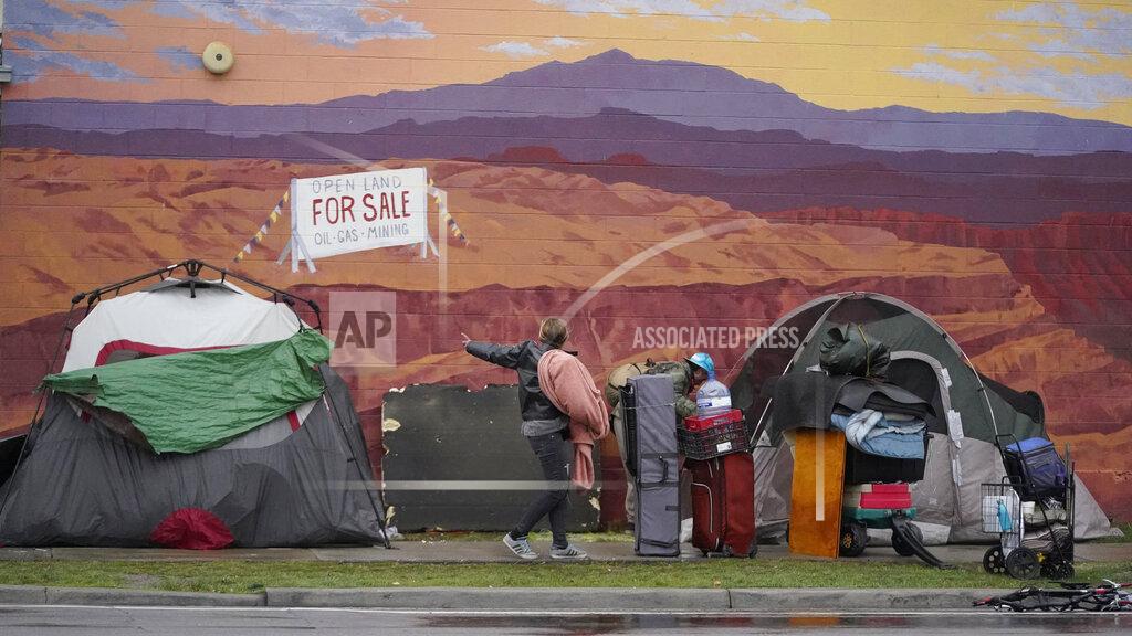 People collect their belongings as Salt Lake County conducts a homeless camp cleanup at the Fleet Block Murals, near a series of murals depicting people killed by police Wednesday, April 14, 2021, in Salt Lake City. Officials call it a cleanup that was necessary to alleviate environmental and health concerns at the site and that the unsheltered people had been offered access to health, housing and other resources ahead of the cleanup. But advocates say the stresses of the coronavirus pandemic have been compounded by a housing crisis and a severe shortage of shelter beds, and the focus should instead be on expanding access to resources. (AP Photo/Rick Bowmer)