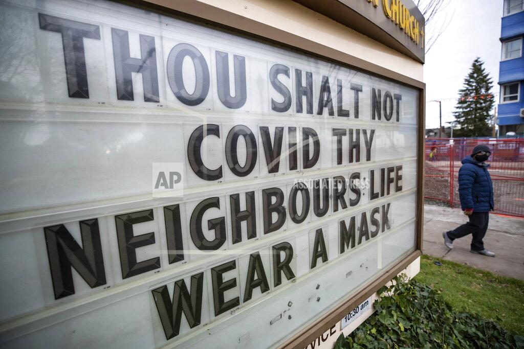 Darryl Dyck A person passes a sign with a message about wearing a face mask outside a church near Royal Columbia Hospital in New Westminster, British Columbia, on Sunday, Nov. 29, 2020. (Darryl Dyck/The Canadian Press via AP)