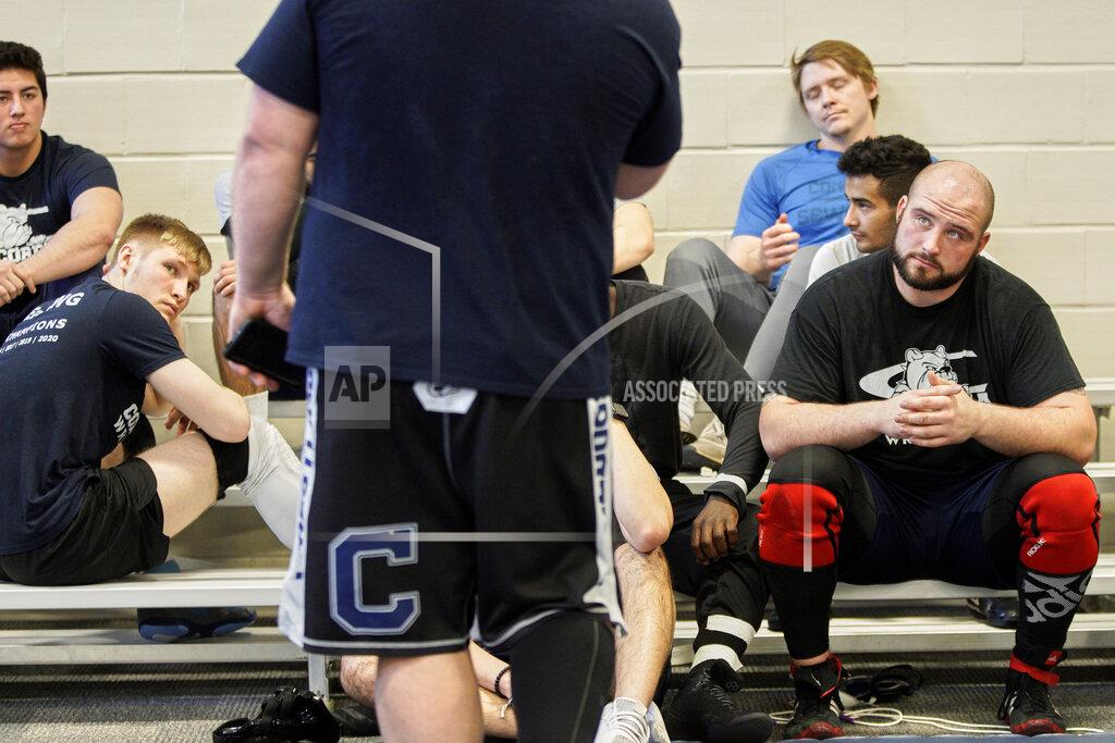 Nati Harnik In this March 2, 2020, photo, former Nebraska football player Tanner Farmer and current wrestler for Concordia University, right, sits with teammates during a briefing by coach Levi Calhoun, in Seward, Neb. A year ago Farmer was thought to be on the rise as an NFL draft prospect. It turned out he went undrafted, so he took a volunteer assistant's job with the Concordia football team and then, quite by accident, discovered he had one semester of eligibility to compete in another sport in the National Association of Intercollegiate Athletics. He chose wrestling. (AP Photo/Nati Harnik)