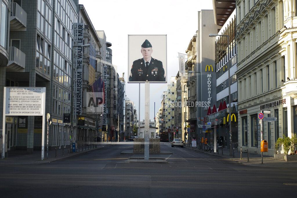 FILE - In this June 9, 2020, file photo, a picture of a former American soldier is displayed at the former U.S. army Checkpoint Charlie in Berlin, Germany. In vowing to pull thousands of U.S. troops from Germany, President Donald Trump is following a pattern of disruptive moves against allies that have dismayed many of his fellow Republicans. Trump has consistently promised to bring American troops home, dismissing the conventional view that a far-flung U.S. military presence, while costly, pays off in the long run by ensuring stability for global trade. Earlier this week he said the 34,500 U.S. troops in Germany would be reduced to 25,000. (AP Photo/Markus Schreiber, File)