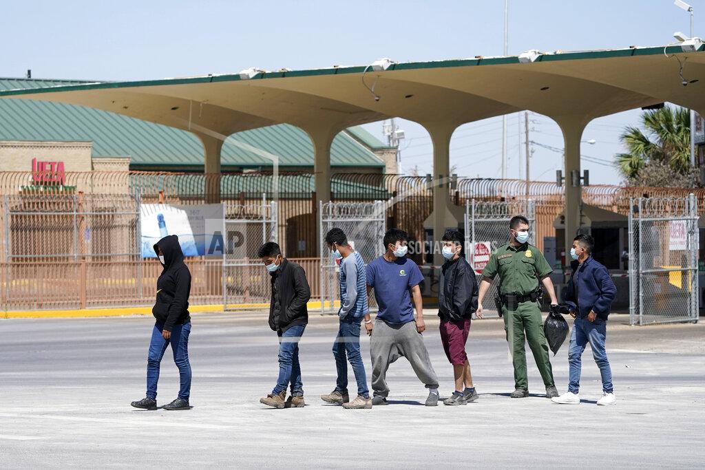 Julio Cortez Migrants who were caught trying to sneak into the United States are led by a U.S. Customs and Border Protection agent, second from right, at the McAllen-Hidalgo International Bridge while being deported to Reynosa, Mexico, Thursday, March 18, 2021, in Hidalgo, Texas. A surge of migrants on the Southwest border has the Biden administration on the defensive. The head of Homeland Security acknowledged the severity of the problem Tuesday but insisted it's under control and said he won't revive a Trump-era practice of immediately expelling teens and children. (AP Photo/Julio Cortez)