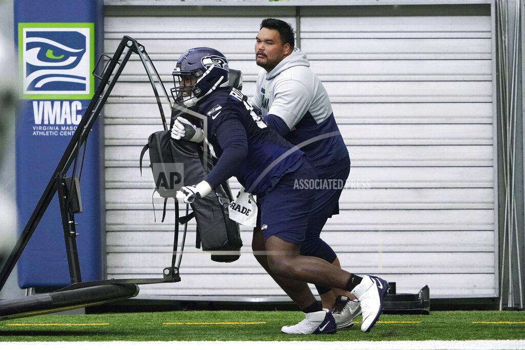 Ted S. Warren Seattle Seahawks offensive tackle Charles Cross, left, hits a blocking sled as assistant offensive line coach Keli'i Kekuewa, right, looks on during NFL football rookie minicamp, Friday, May 6, 2022, in Renton, Wash. (AP Photo/Ted S. Warren)