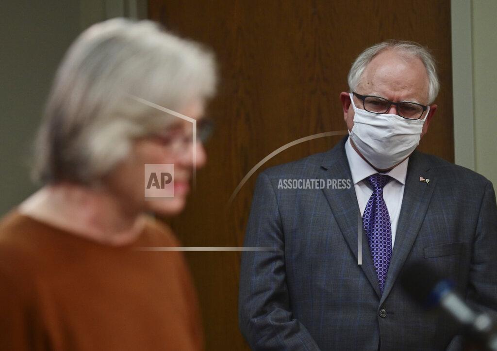 Minnesota Gov. Tim Walz, right, listens to Minnesota Health Commissioner Jan Malcolm as she provides an update on the state's response to the coronavirus pandemic, during a news conference in St. Paul, Minn., Wednesday, May 27, 2020. (John Autey/Pioneer Press via AP, Pool)
