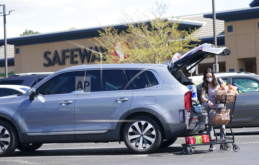 David Zalubowski In this Wednesday, May 19, 2021, photograph, a shopper wearing a face mask loads her purchases into a sports-utility vehicle outside a Safeway grocery store in Aurora, Colo. Many workers in retail sales jobs who are fully vaccinated are concerned about risks posed as retailers change their mask-wearing policies for customers. (AP Photo/David Zalubowski)